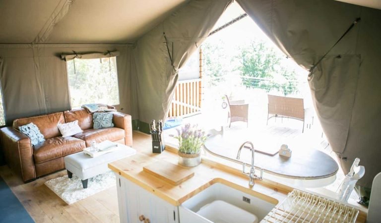 Open-plan glamping kitchen and living space with outdoor deck views and natural light flooding into the lodge.