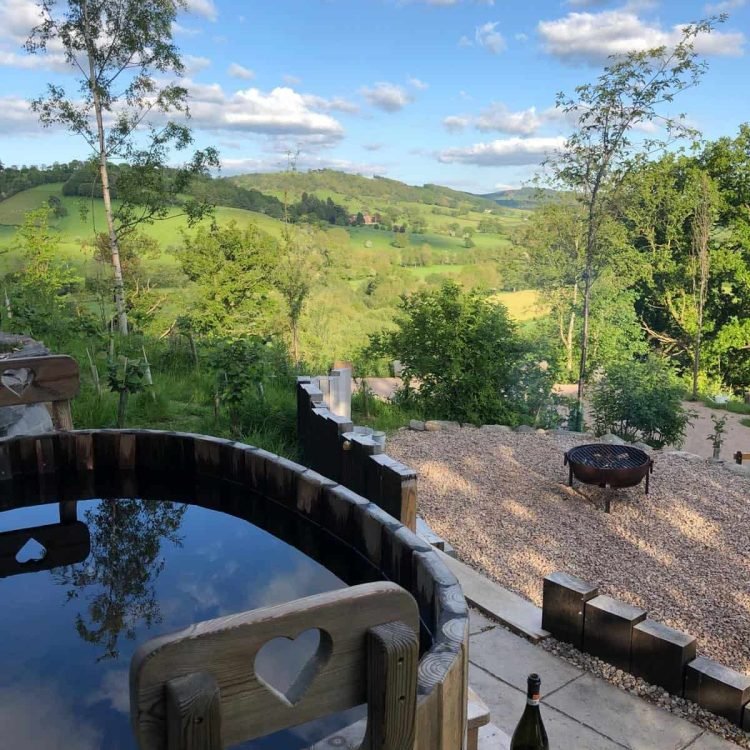 Wood-fired hot tub with romantic countryside views over the rolling Mid Wales landscape at Oaklands Safari Tent.