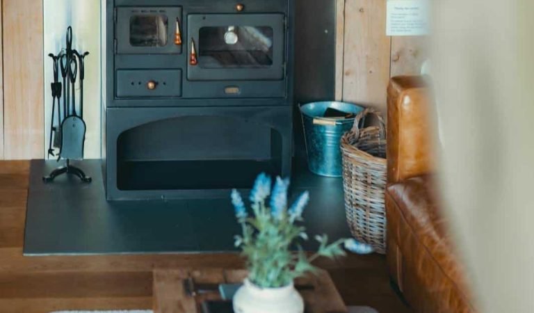 Log burner in the safari tent living area at Oaklands, creating a warm and welcoming atmosphere with rustic wood-panelled walls.