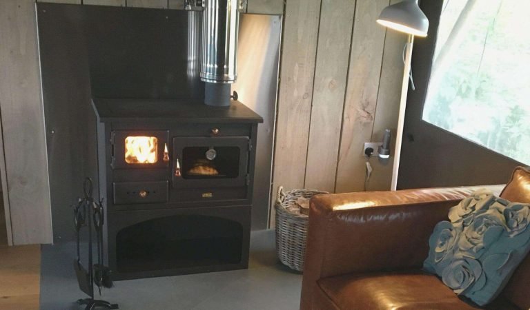 a lit fire and stove next to a sofa in a tent