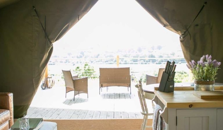 Bright open-plan safari tent interior with views across the Welsh countryside from the private decking.