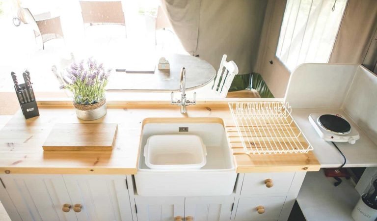 Farmhouse-style kitchenette inside the Oaklands safari tent, with wooden countertops, ceramic sink and countryside décor.