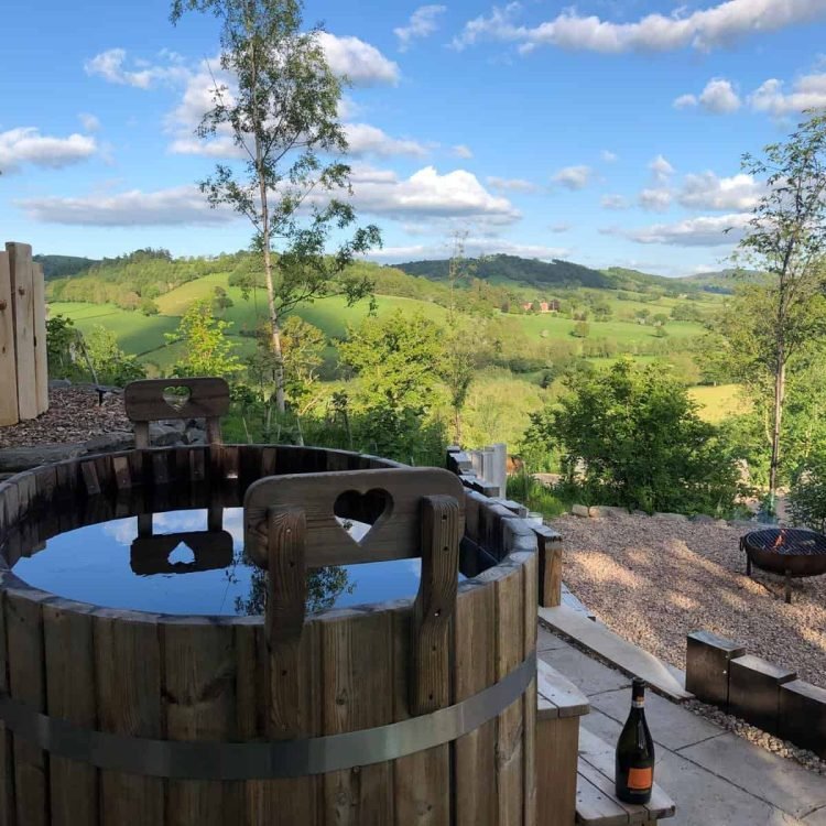 Romantic wood-fired hot tub with panoramic hill views at Oaklands Glamping in Mid Wales.