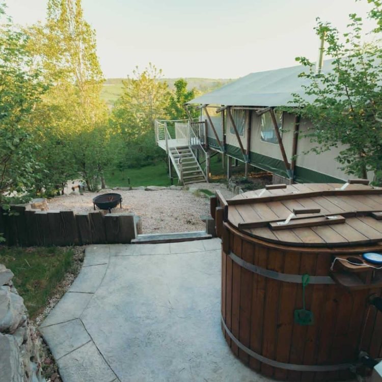 Private wood-fired hot tub and fire pit overlooking rolling green hills at Oaklands Glamping.