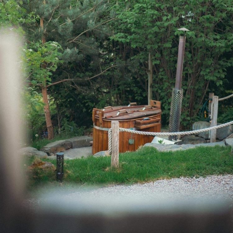 Wood-fired hot tub outside the safari tent with clear blue skies and scenic rural views.