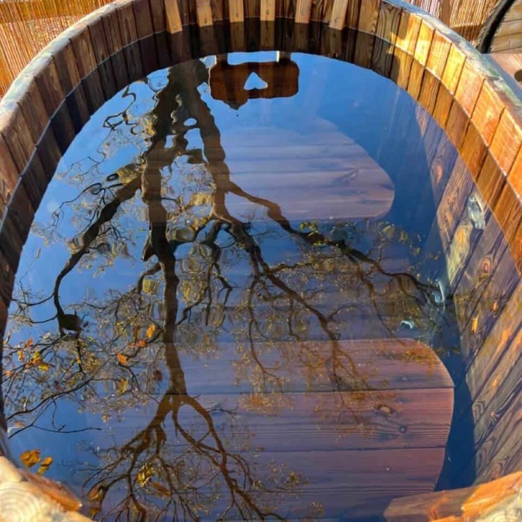 a top view of a wooden hot tub with a reflection of a tree