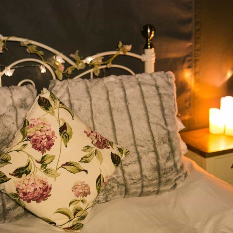 Close-up of plush cushions and soft luxury bedding on the Hypnos mattress inside the safari tent