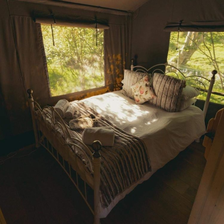 Luxury safari tent bedroom with Hypnos mattress, soft bedding and woodland views at Oaklands Glamping